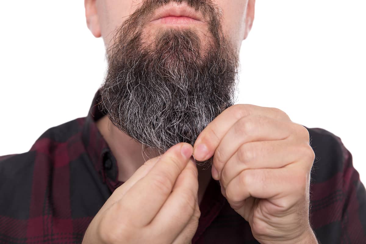 Mann massiert Bartöl in seinen Bart ein