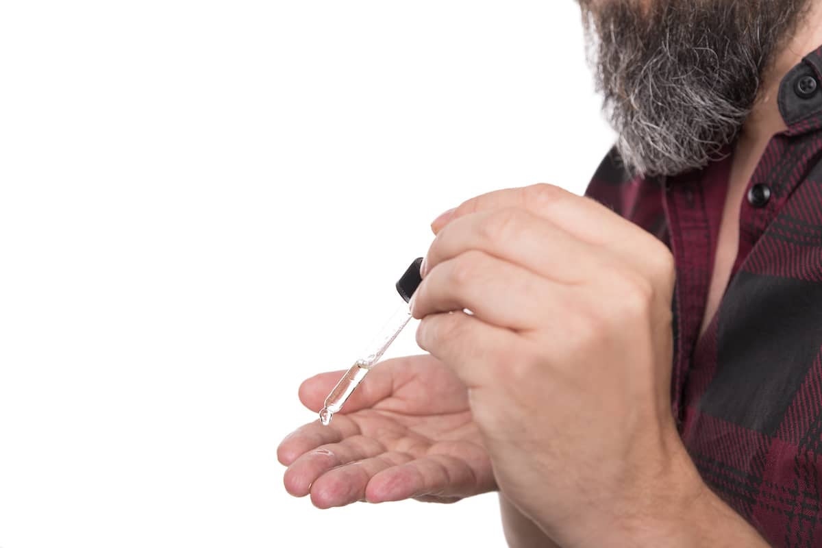 Mann gibt Bartöl auf die Hand