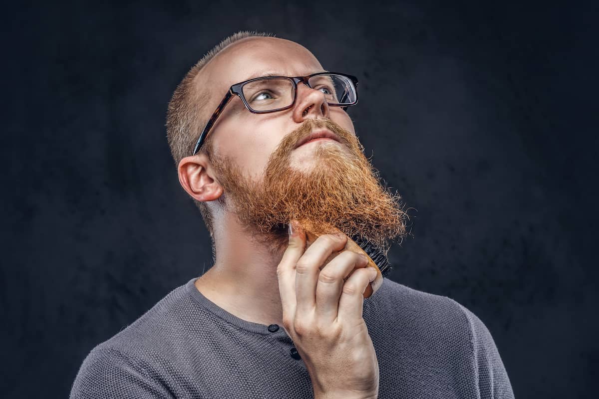 Mann bürstet Bart mit Bartbürste