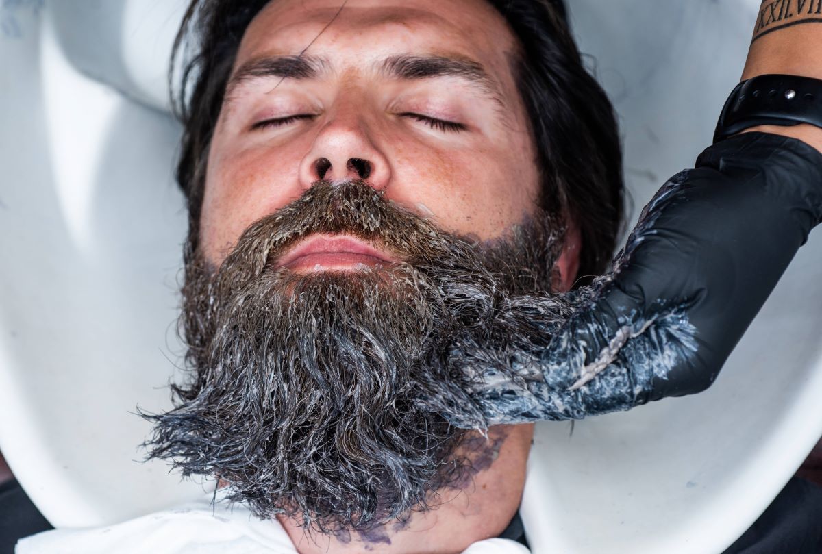 Vollbart eines Mannes wird vom Barbier gewaschen 