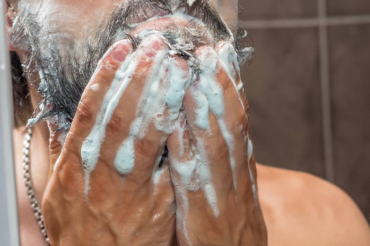 Mann wäscht sich den Bart mit Bartshampoo vor dem Bart schneiden