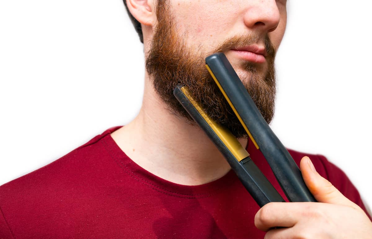 Mann benutzt Bartglätter Glätteisen um die Barthaare zu glätten