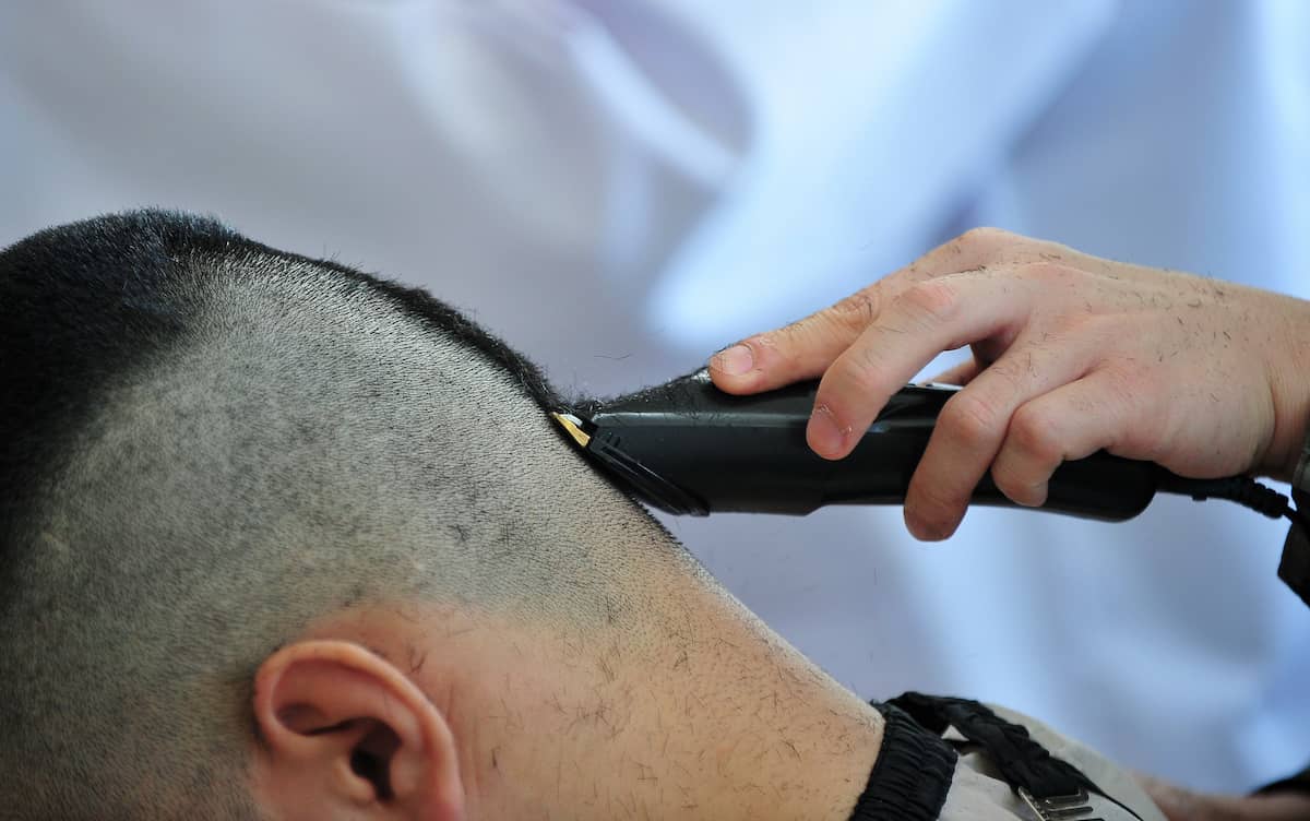 Mann bekommt einen Crew Cut mit einer Haarschneidemaschine rasiert