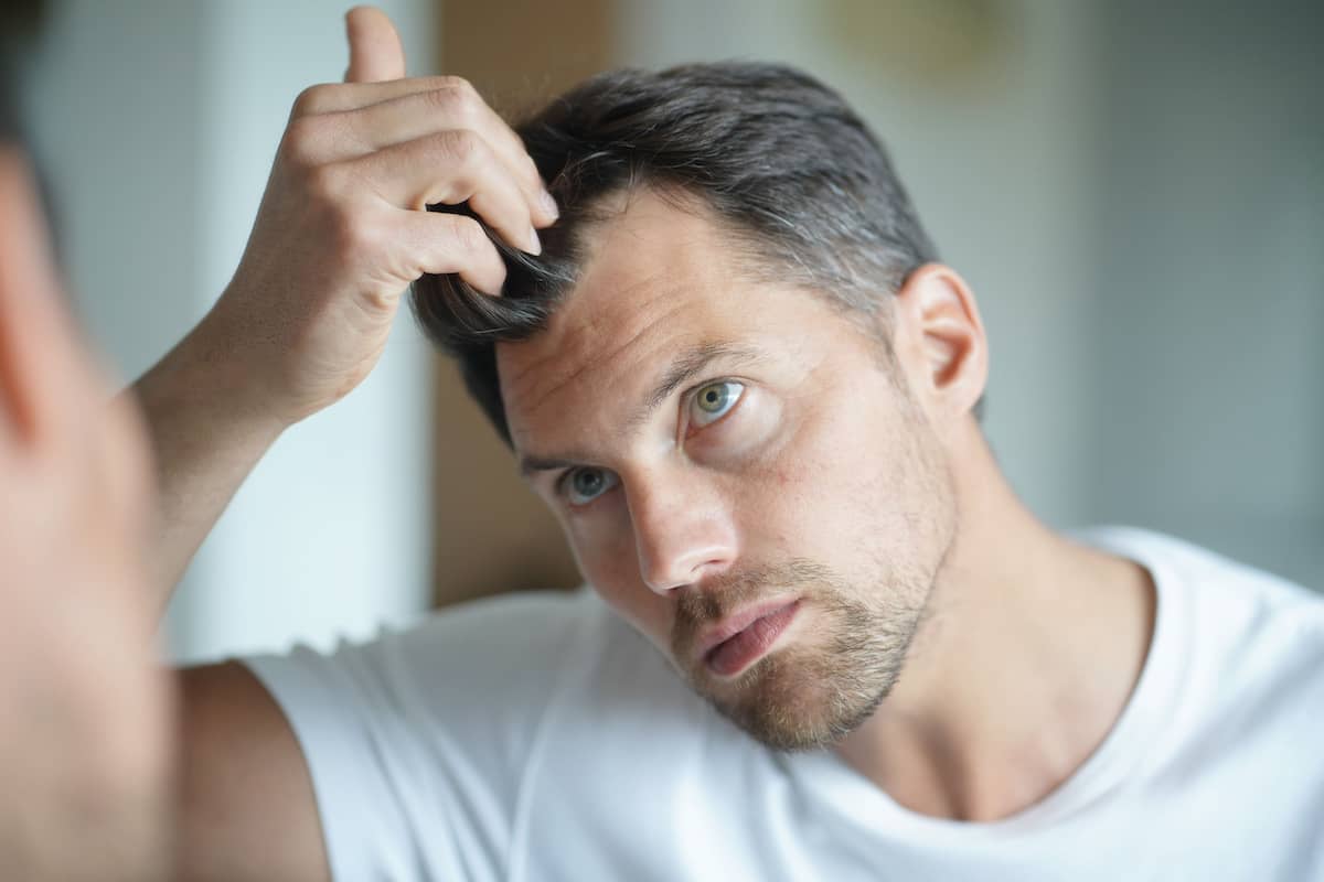 Mann denkt über Frisuren für Geheimratsecken nach