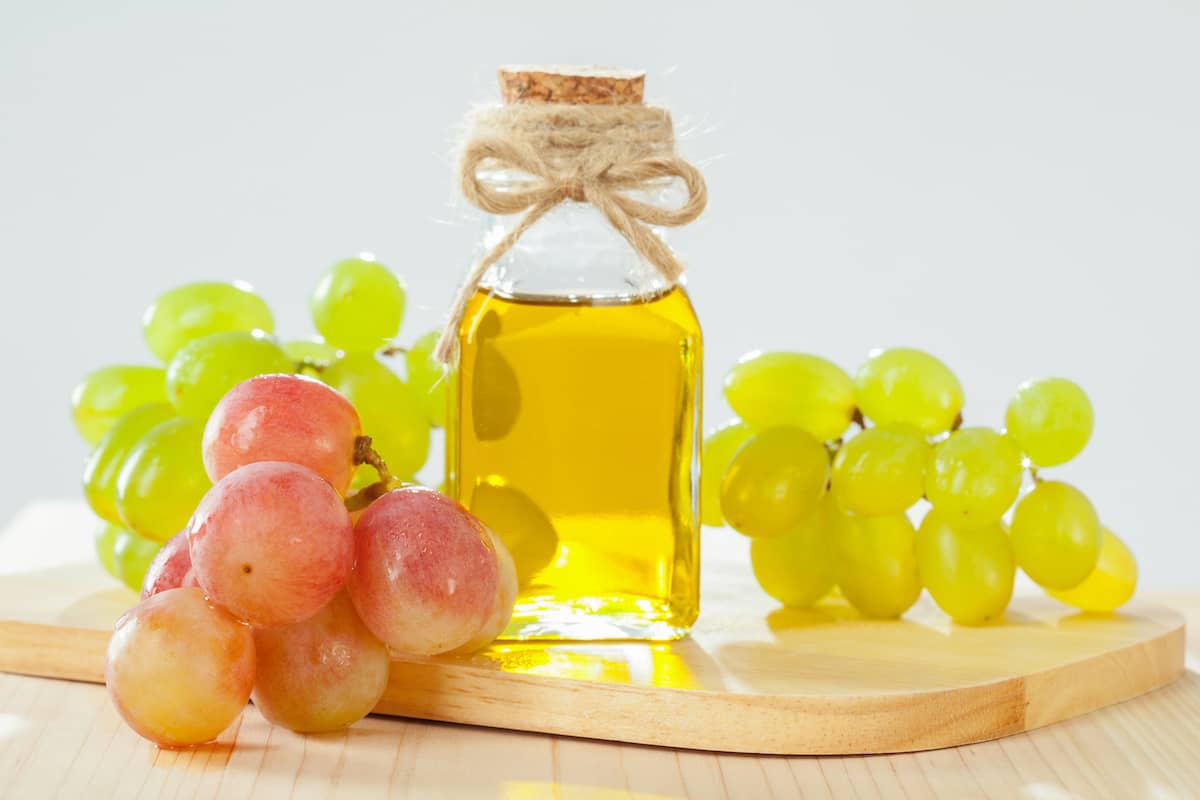 Traubenkernöl im Fläschchen mit Weintrauben arrangiert
