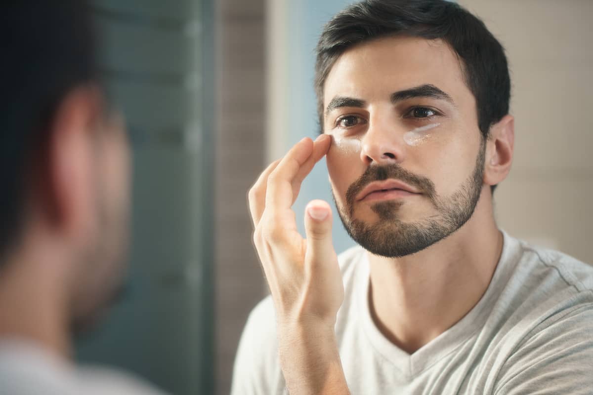 Mann probiert Gesichtspflege für Männer vor dem Spiegel aus