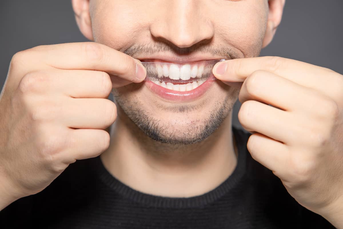 Mann verwendet Bleaching Strip zur Zahnaufhellung zuhause