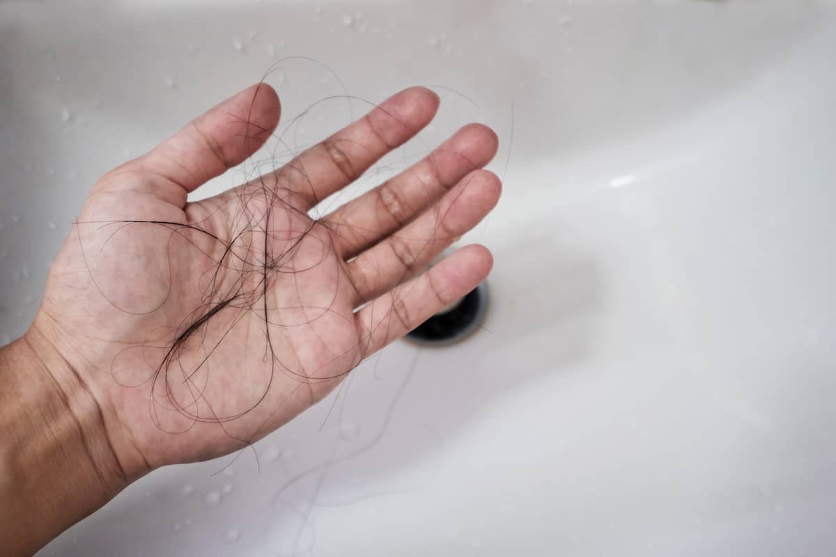 Mann sammelt ausgefallene Haare aus der Dusche ein
