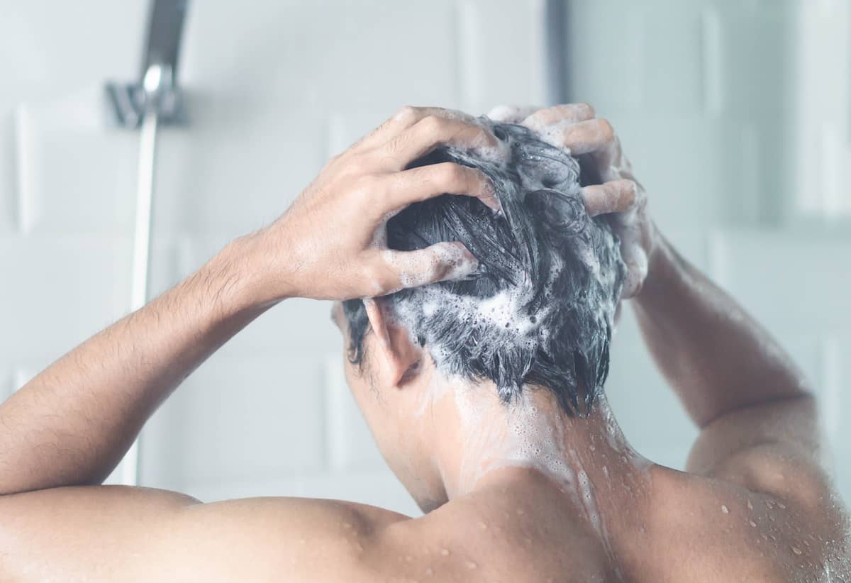 Mann shampooniert sich die Haare mit Koffeinshampoo