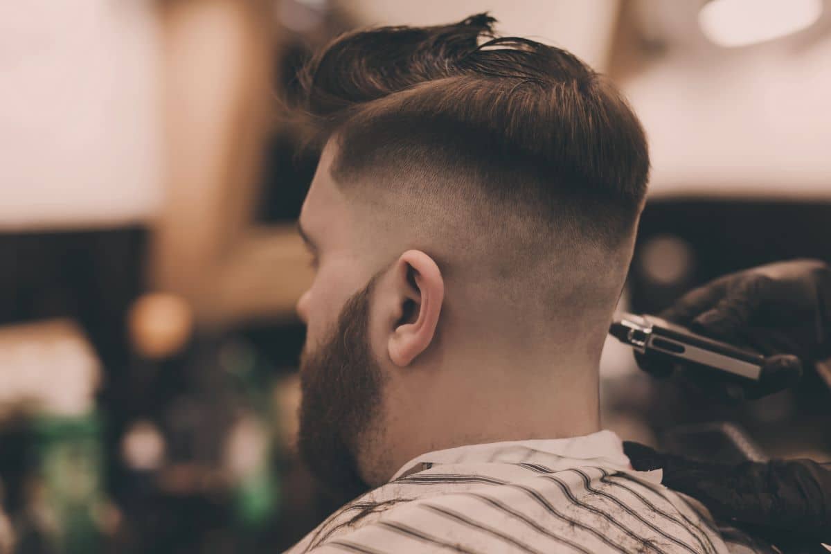 Mann sitzt beim Friseur und kriegt Haare geschnitten